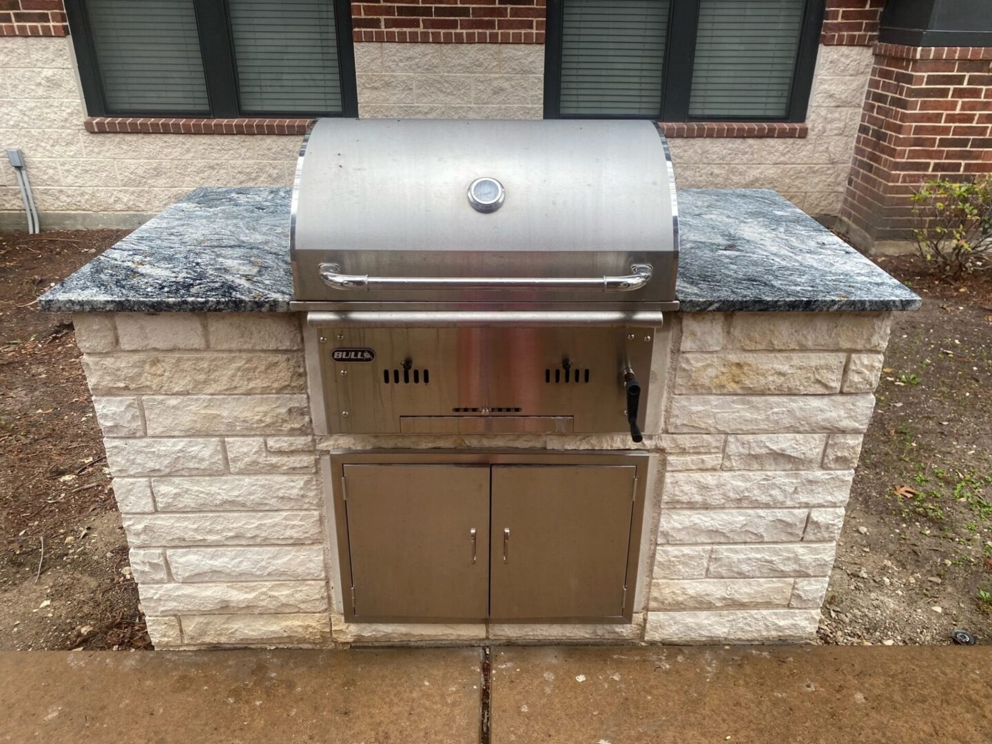 A grill sitting on top of a brick wall.